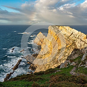 Rainbow formed by storms on the horizon of the sea seen from the cliffs of the shore, Asturias, Spain