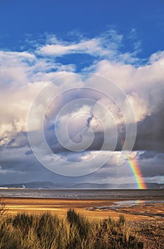 Rainbow going through clouds over the sea, at Swansea bay, south Wales.