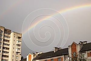 Rainbow in the gray sky over the rooftops
