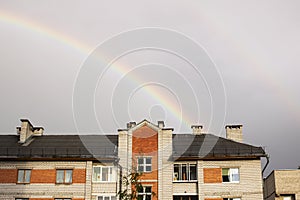 Rainbow in the gray sky over the rooftops