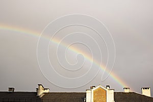 Rainbow in the gray sky over the rooftops