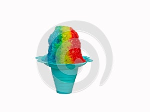 Rainbow Hawaiian Shave ice, Shaved ice or snow cone in a blue flower shaped cup against a white background.
