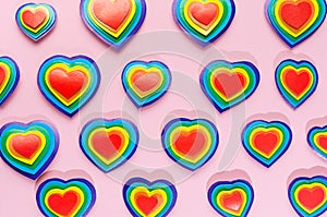 Rainbow hearts on pastel pink background, pattern, top view.