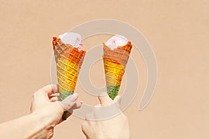rainbow ice cream cone - two hands holdling ice cream cones in rainbow colors at hot summer day