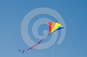 Rainbow kite design flying on blue sky.