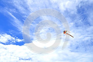 Rainbow kite flying in blue sky.