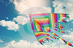 Rainbow kite flying in blue sky with clouds. Freedom and summer holiday