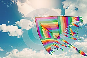 Rainbow kite flying in blue sky with clouds. Freedom and summer holiday photo