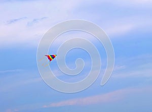 A rainbow kite flying on the sky.