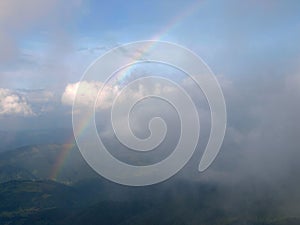 Rainbow between the land and clouds high in Carpathian Mountains