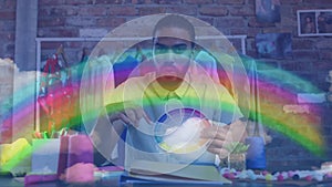 Rainbow light trails against african american male fashion designer holding a color pallete