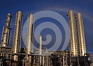 A rainbow looms  over a refinery gleaming in the late day sun. photo