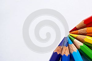 A rainbow made of red, orange, yellow, green, blue, dark blue and purple colored pencils.