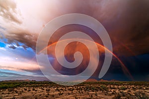 Rainbow and monsoon storm at sunset