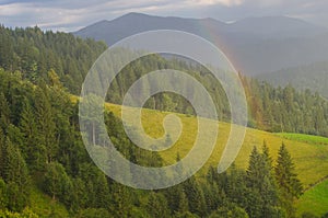 Rainbow in the mountain valley after rain. Beautiful landscape.