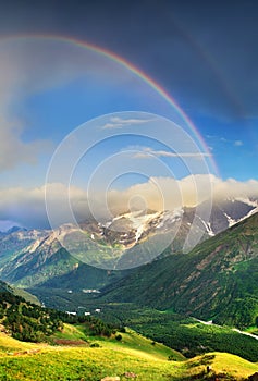 Rainbow in the mountain valley during rain