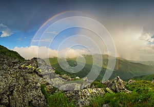 Rainbow in the mountain valley during rain