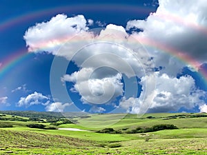 Rainbow nature landscape contryside green grass field trees  and sun beam on cloudy fluffy  blue and pink  sky