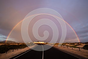 Rainbow over dunes and a dune road. Corralejo National Park, morning, Las Palmas Province, Fuerteventura, Canary Islands, Spain