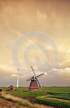 Rainbow over Dutch windmill at sunset