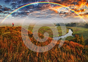 rainbow over the meadow. tourist enjoys the view