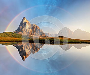 Rainbow over Mountain lake reflection, Dolomites, Passo Giau