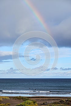 Rainbow over the ocean. Rainbow over the sea. Waves crashing on shoreline