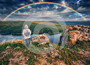 Rainbow over the river. woman on a cliff above the canyon