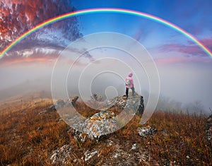 Rainbow over the river. woman on a cliff above the canyon