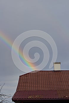 rainbow over the roof, rainbow in the cloudy sky over the roof of the house