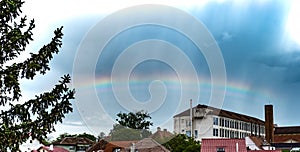 Rainbow over rooftops with rain clouds