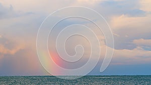 Rainbow Over The Sea. Rainbow In Cloudy Sky Over Sea With Waves. Static view.