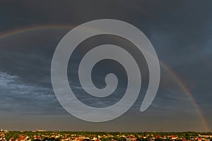 Rainbow over stormy sky. Double rainbow over city with a dramatic sky in the background. Gloomy dark sky in the