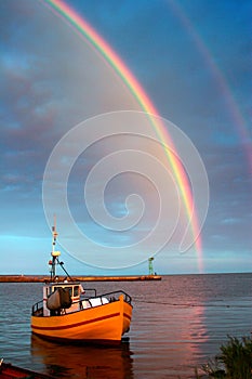 Rainbow over the water, view of the boat and the bay