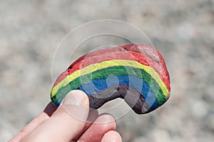 Rainbow painting on stone pebble in hand