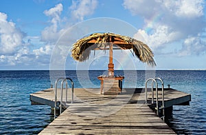 A rainbow with a palapa in front with a nice view of the caribbean sea