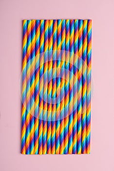 Rainbow paper cocktail straws on pink background