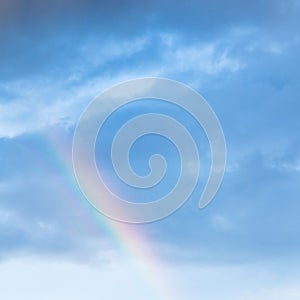 Rainbow in rain clouds in blue evening sky