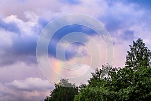 Rainbow after rain in a cloudy sky among dramatic clouds