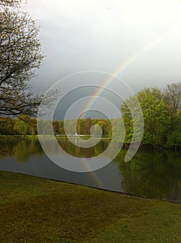 A rainbow with reflexion over the Lake Umminger, Germany.