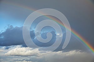 Rainbow in the sky after the rain. Evening sky. White clouds. You can see the sky through the storm clouds. High in the