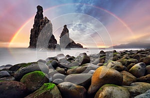 Rainbow sunrise rocky coast with monumental rocky cliff and blurred sea water. Madeira island, Portugal