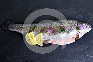 Rainbow trout with lemon and fresh thyme on black background