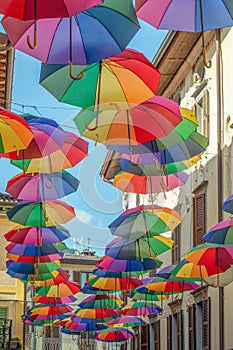 Rainbow umbrellas on blue sky background. Many colorful umbrellas, street decoration for festivals. Concept diversity