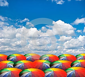 Rainbow umbrellas on cloudy sky