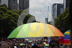 Rainbow umbrellas under the sun carried by the crowd at the LGBTTI pride march in avenue de la reforma Mexico city