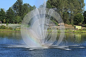 Rainbow from a water fountain in a small lake