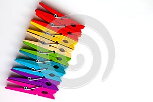 Rainbow of wooden clothespins on white background with copy space/diversity concept