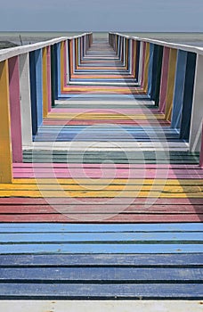 Rainbow wooden pier by the sea Bright sky background. End of walkway. Multi-colored floor