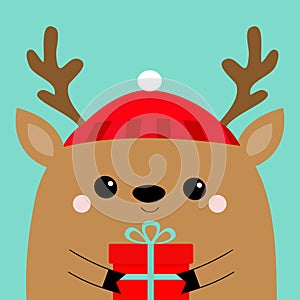 Raindeer deer head face holding gift box. Red hat, nose, horns. Merry Christmas. Happy New Year. Cute cartoon kawaii baby